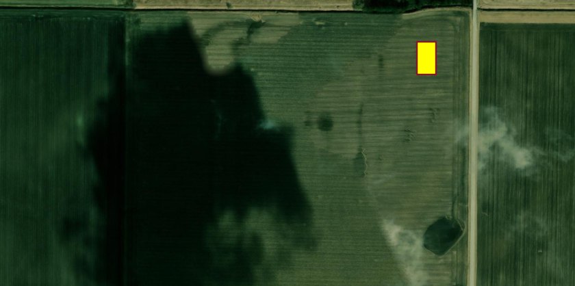 An aerial photograph of a field with one small yellow rectangle, the plot graphic, near its northeast corner