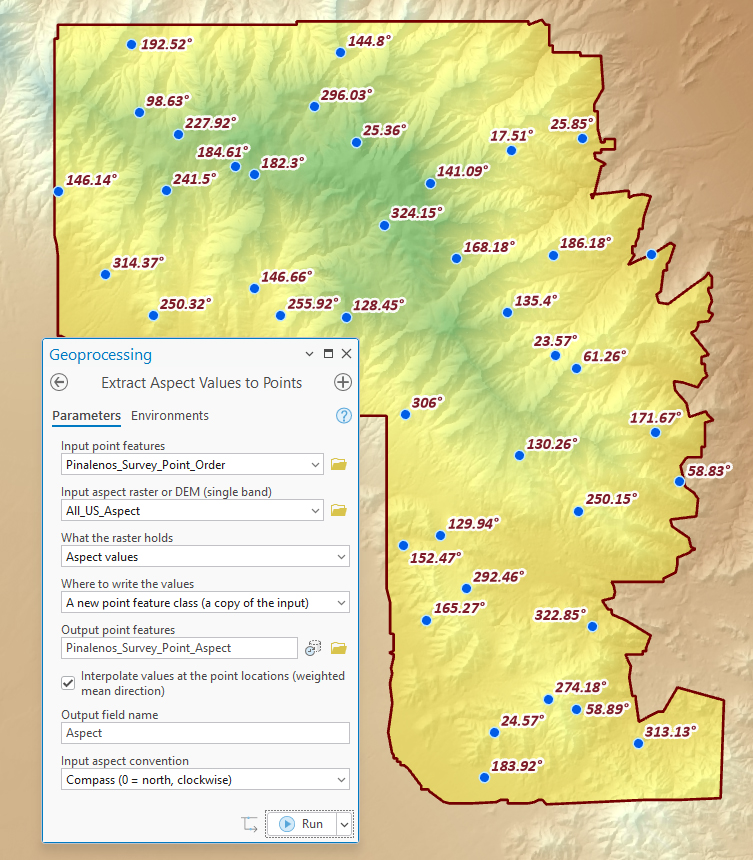 Survey points scattered across a mountain range outlined in dark red, over a shaded elevation map, each labeled with its aspect in degrees, such as 192.52, 25.36 and 313.13, with the Extract Aspect Values to Points pane over the lower left: Input point features Pinalenos_Survey_Point_Order, Input aspect raster or DEM All_US_Aspect, What the raster holds set to Aspect values, Where to write the values set to A new point feature class (a copy of the input), Output point features Pinalenos_Survey_Point_Aspect, Interpolate values checked, Output field name Aspect, Input aspect convention Compass (0 = north, clockwise).
