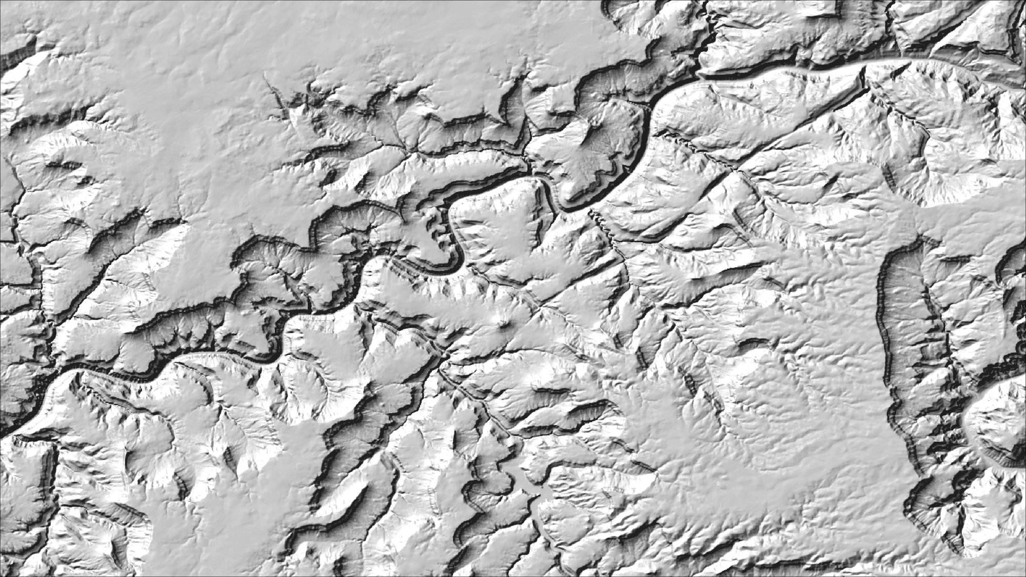 A gray hillshade of a winding canyon system with the sun in the northwest: the canyon reads correctly as a gorge cut below the plateau, with its side canyons branching away from the main channel