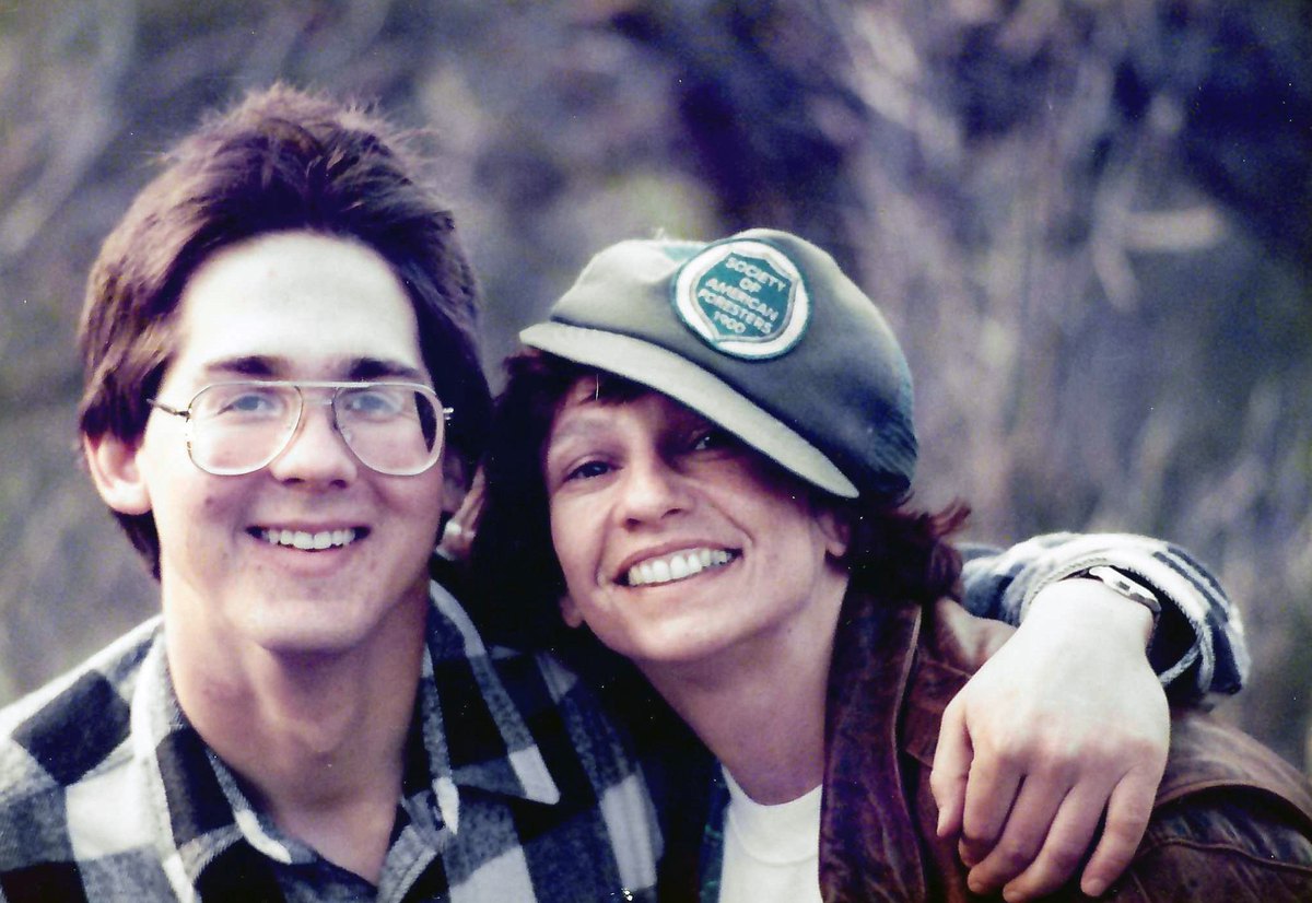 Jeff Jenness and Lois Engelman, smiling, outdoors among bare winter branches; Lois wears a Society of American Foresters cap