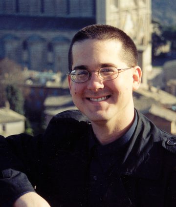 Jeff Jenness in glasses and a dark shirt, smiling, in front of the Cathedral of Orvieto