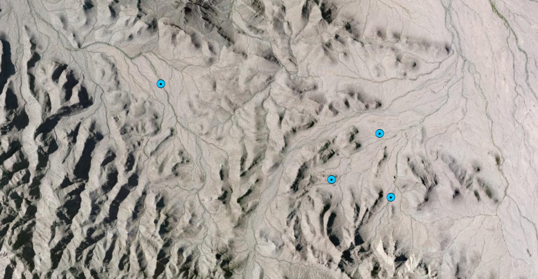 Aerial terrain with four blue points, three clustered near each other and one alone to the right