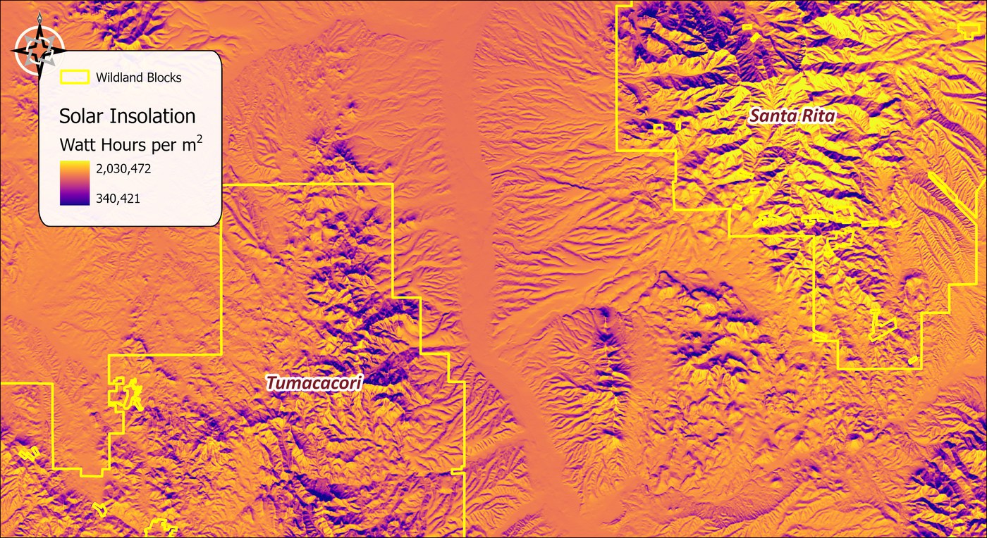 Annual solar insolation over the study area in watt-hours per square meter, from 340,421 in deep purple on shaded north-facing slopes to 2,030,472 in yellow on open south-facing ground, with the wildland blocks outlined in yellow