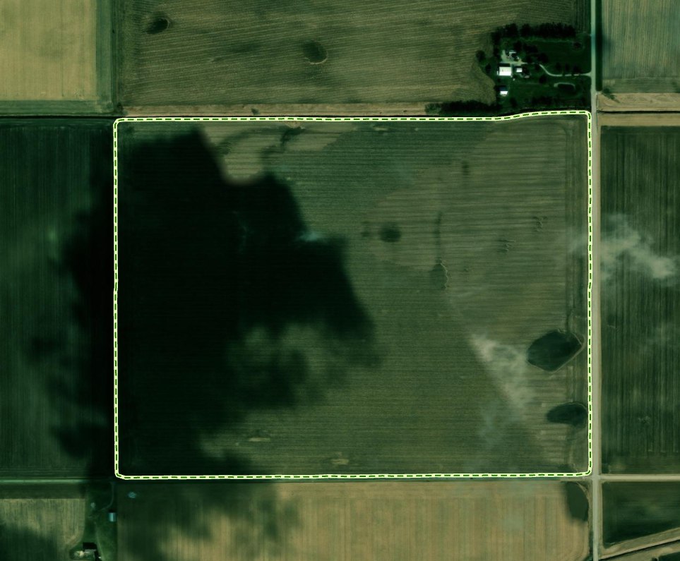 An aerial photograph of a rectangular crop field outlined with a dashed yellow-green boundary, with farm buildings beyond its northeast corner